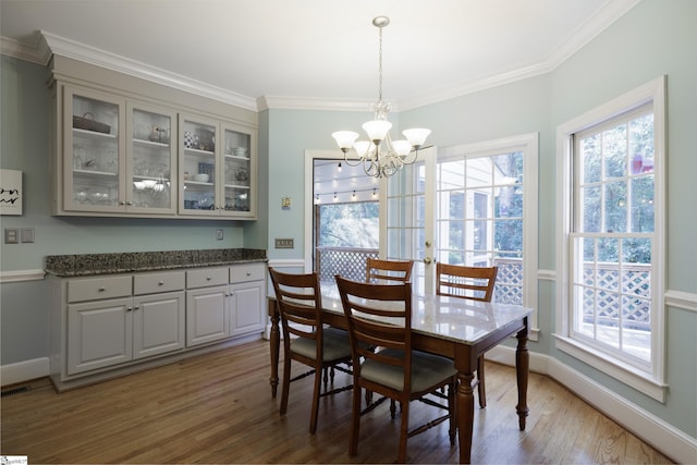 dining space with a notable chandelier, wood-type flooring, and ornamental molding