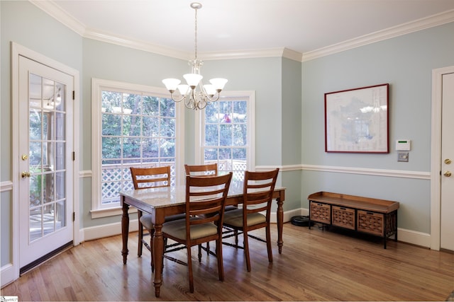 dining space featuring light wood-type flooring, crown molding, and an inviting chandelier