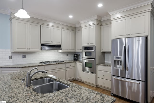 kitchen featuring pendant lighting, sink, light stone countertops, appliances with stainless steel finishes, and tasteful backsplash