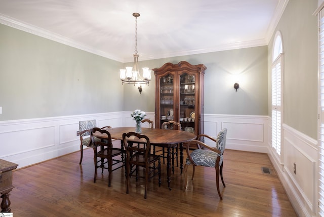 dining room featuring an inviting chandelier, crown molding, and dark wood-type flooring