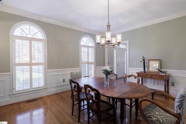 dining room featuring crown molding, wood-type flooring, and a notable chandelier