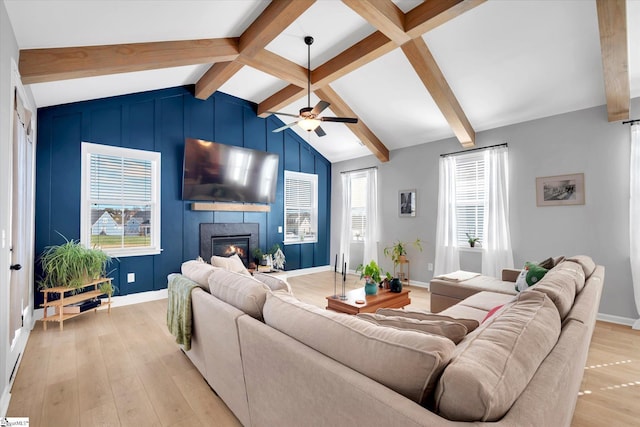 living room featuring vaulted ceiling with beams, light hardwood / wood-style floors, a wealth of natural light, and ceiling fan