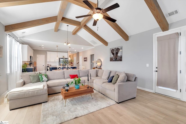 living room featuring ceiling fan with notable chandelier, lofted ceiling with beams, and light hardwood / wood-style floors