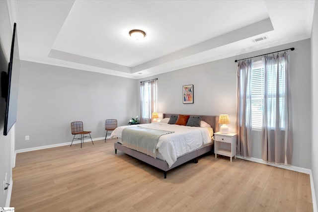 bedroom featuring a raised ceiling and light wood-type flooring