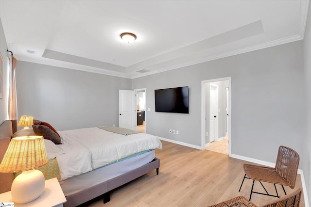 bedroom with a raised ceiling, ensuite bathroom, light hardwood / wood-style flooring, and ornamental molding