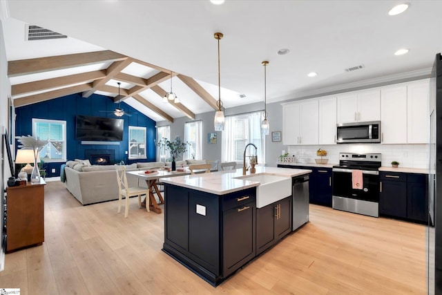 kitchen featuring pendant lighting, a kitchen island with sink, light hardwood / wood-style flooring, white cabinetry, and stainless steel appliances