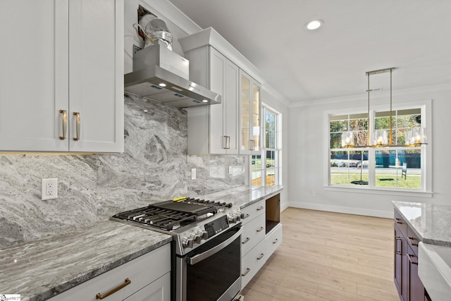 kitchen featuring white cabinetry, wall chimney exhaust hood, light stone counters, light hardwood / wood-style flooring, and stainless steel range with gas stovetop