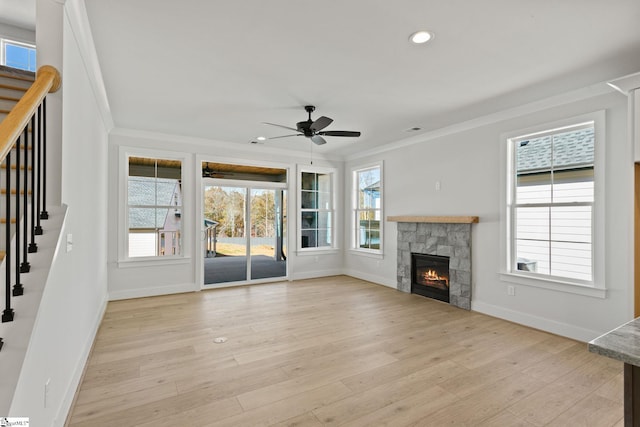 unfurnished living room featuring a stone fireplace, ceiling fan, crown molding, and light hardwood / wood-style floors