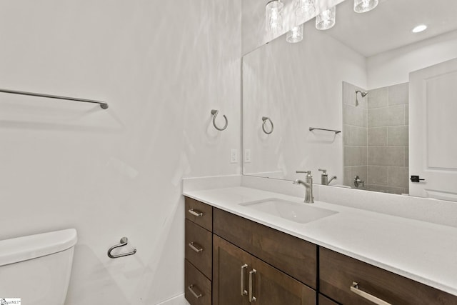 bathroom featuring vanity, toilet, and a tile shower