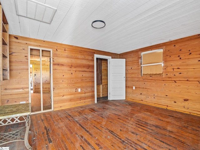 unfurnished bedroom with wood-type flooring and wooden walls