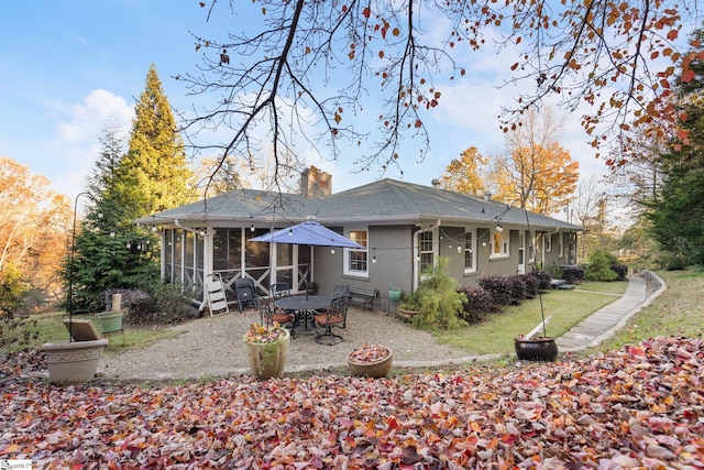 back of property with a lawn, a sunroom, and a patio