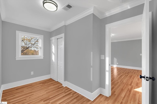 unfurnished bedroom with light hardwood / wood-style flooring, a closet, and ornamental molding