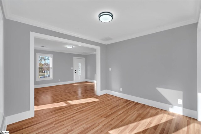 empty room with light hardwood / wood-style floors and crown molding