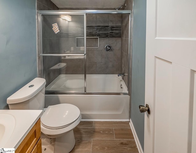 full bathroom featuring hardwood / wood-style flooring, vanity, toilet, and combined bath / shower with glass door