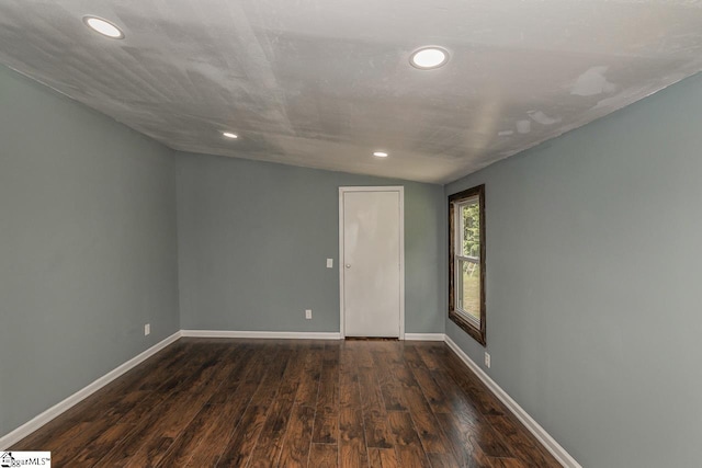 empty room featuring dark hardwood / wood-style floors, a textured ceiling, and vaulted ceiling