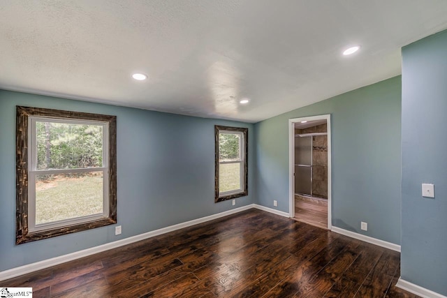 spare room featuring a textured ceiling, dark hardwood / wood-style flooring, and vaulted ceiling