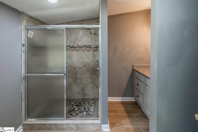 bathroom with vanity, a shower with shower door, and lofted ceiling