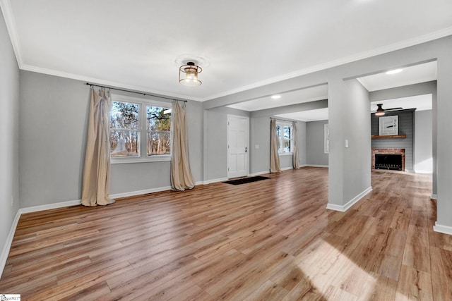 unfurnished room with a fireplace, crown molding, and light hardwood / wood-style flooring