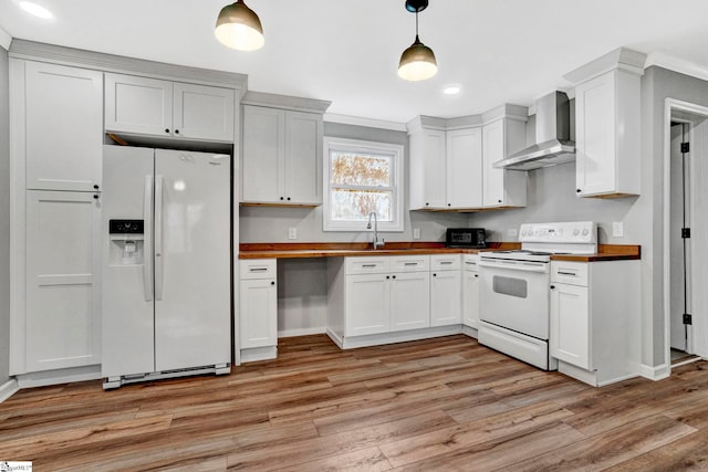 kitchen featuring wall chimney range hood, wood counters, light hardwood / wood-style floors, pendant lighting, and white appliances