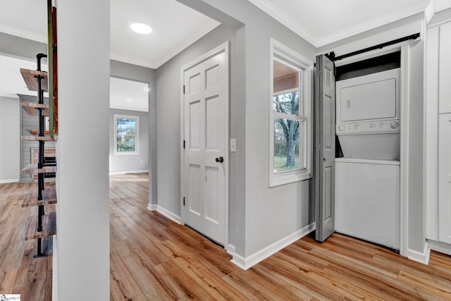 interior space featuring light wood-type flooring, stacked washer and dryer, and ornamental molding