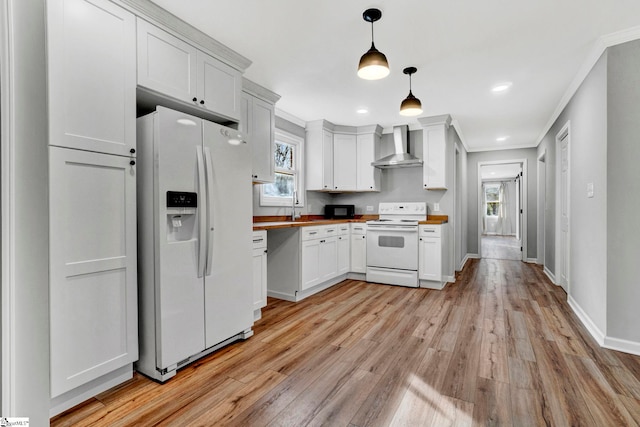 kitchen with wall chimney exhaust hood, wooden counters, decorative light fixtures, white appliances, and light wood-type flooring