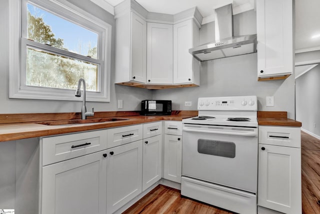 kitchen with wooden counters, white range with electric cooktop, a wealth of natural light, and wall chimney exhaust hood