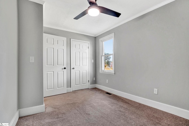 unfurnished bedroom with ceiling fan, a closet, carpet floors, and ornamental molding