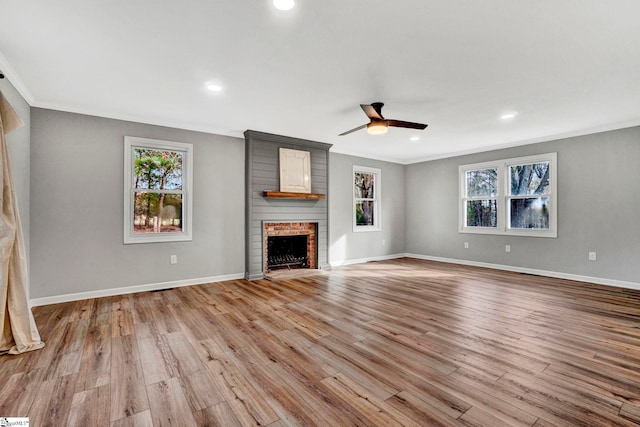 unfurnished living room featuring ceiling fan, ornamental molding, a fireplace, and light hardwood / wood-style flooring