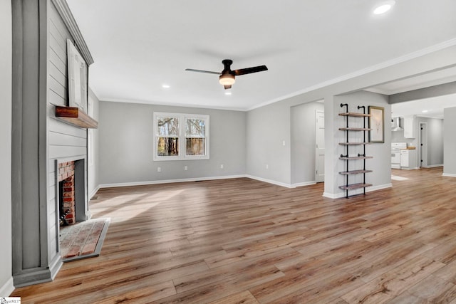 unfurnished living room with light hardwood / wood-style floors, crown molding, and a brick fireplace