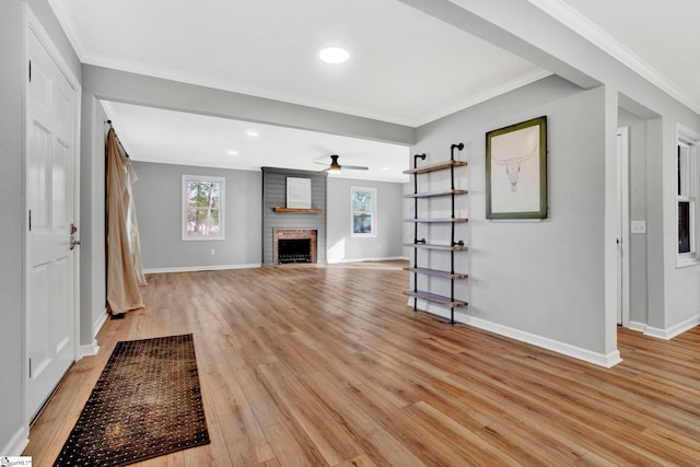 unfurnished living room with light hardwood / wood-style flooring, ornamental molding, and a brick fireplace