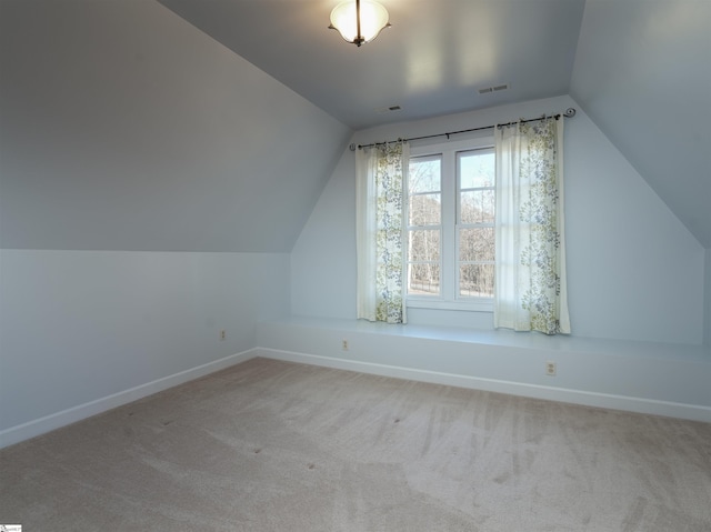 additional living space featuring light colored carpet and vaulted ceiling