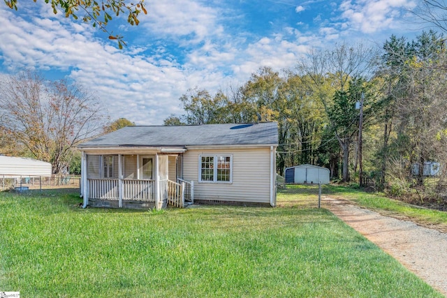 view of front facade with a porch, an outbuilding, and a front yard