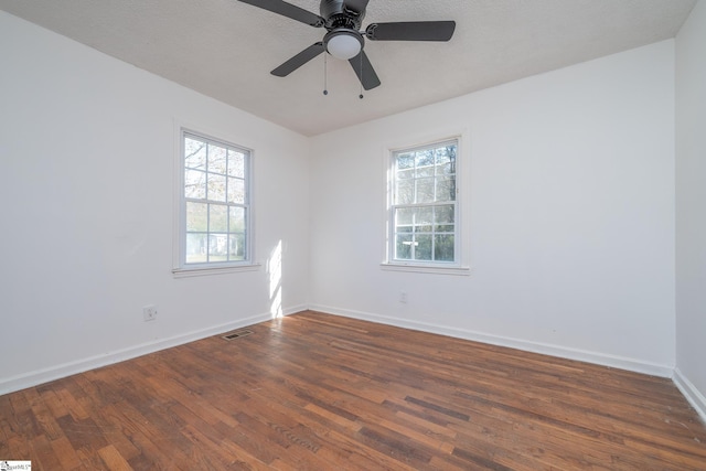 spare room with a textured ceiling, ceiling fan, and dark wood-type flooring