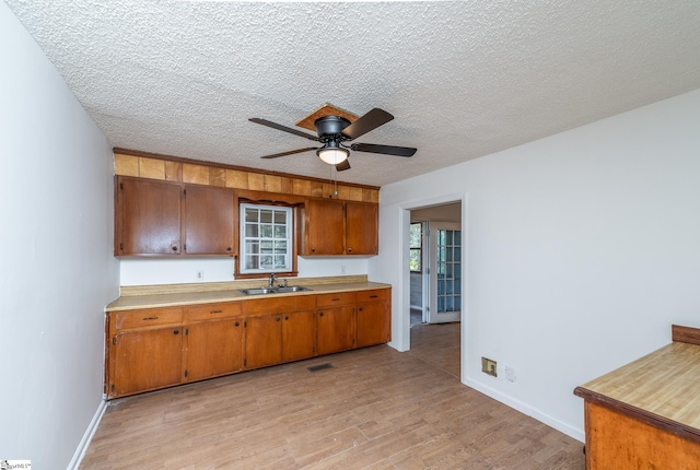 kitchen with a textured ceiling, light hardwood / wood-style floors, ceiling fan, and sink