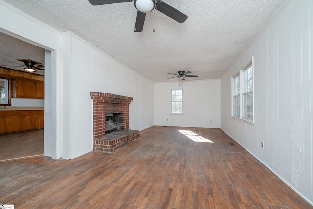 unfurnished living room with a textured ceiling, dark wood-type flooring, and a brick fireplace