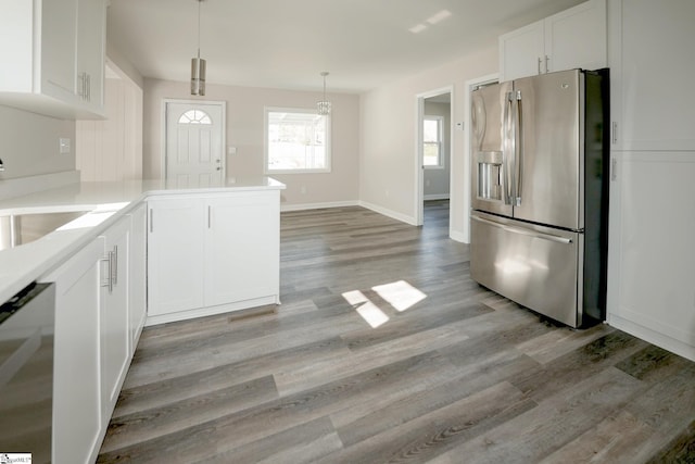 kitchen with kitchen peninsula, light hardwood / wood-style flooring, stainless steel fridge with ice dispenser, white cabinetry, and hanging light fixtures