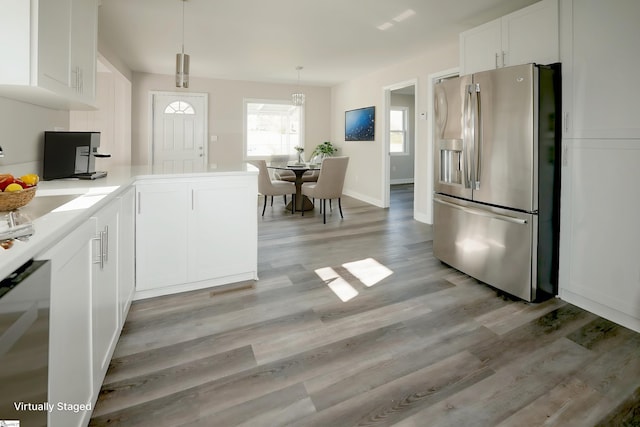 kitchen with pendant lighting, white cabinets, stainless steel fridge, light hardwood / wood-style floors, and kitchen peninsula