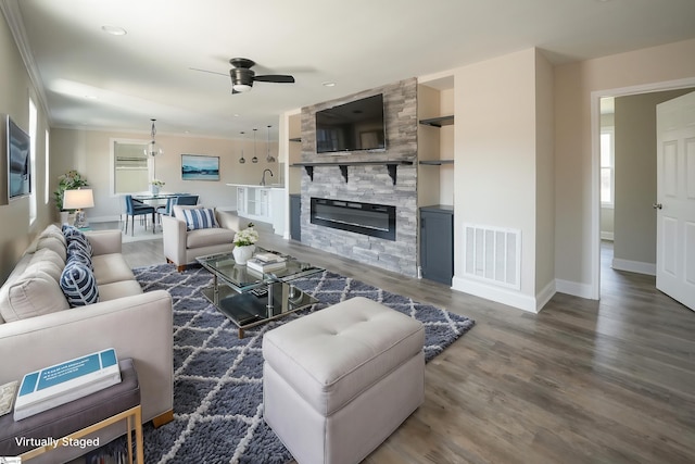 living room featuring built in shelves, ceiling fan, sink, dark hardwood / wood-style floors, and a fireplace