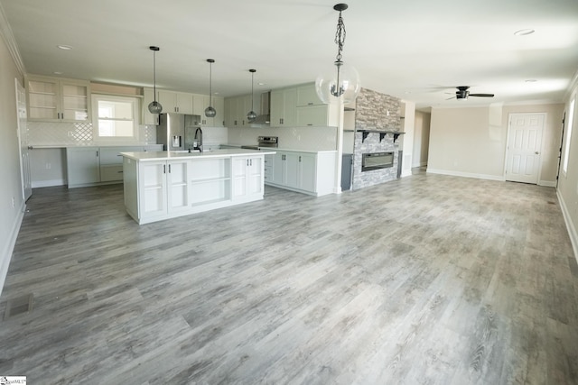 kitchen with stainless steel refrigerator with ice dispenser, hardwood / wood-style floors, pendant lighting, a kitchen island with sink, and ceiling fan with notable chandelier