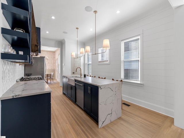 kitchen featuring light stone countertops, light hardwood / wood-style floors, decorative light fixtures, and appliances with stainless steel finishes