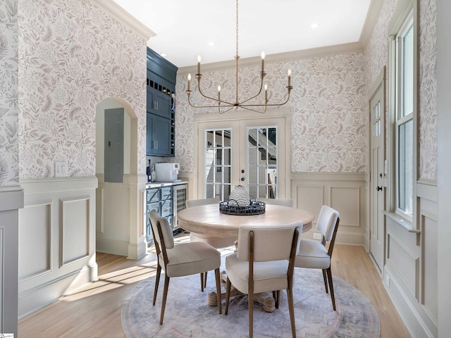 dining space featuring light wood-type flooring, crown molding, beverage cooler, and french doors