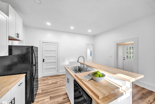 kitchen with wood counters, sink, a center island with sink, and black appliances