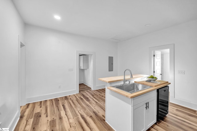 kitchen featuring light hardwood / wood-style floors, sink, white cabinets, electric panel, and an island with sink