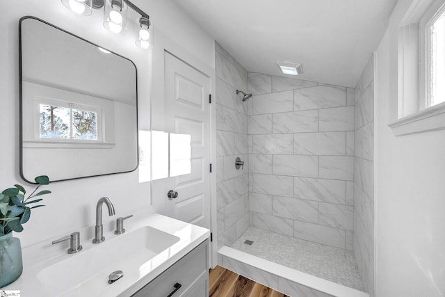 bathroom featuring tiled shower, wood-type flooring, and vanity