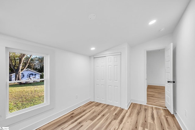 unfurnished bedroom featuring a closet, lofted ceiling, and light hardwood / wood-style flooring