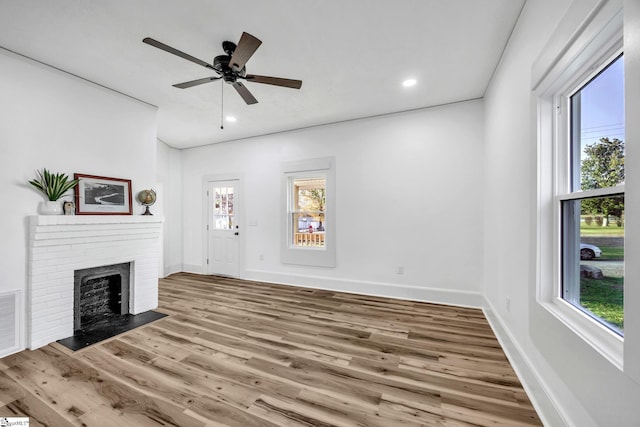 unfurnished living room with ceiling fan, a fireplace, and light hardwood / wood-style floors