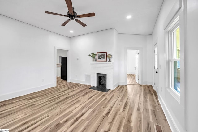 unfurnished living room featuring a fireplace, light hardwood / wood-style flooring, and ceiling fan