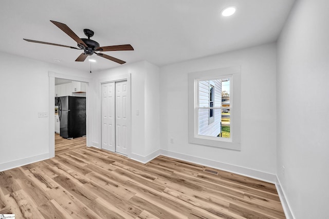 unfurnished bedroom featuring a closet, ceiling fan, black refrigerator, and light hardwood / wood-style flooring