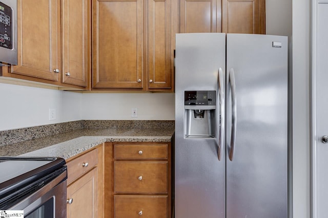 kitchen featuring stainless steel refrigerator with ice dispenser and stone counters