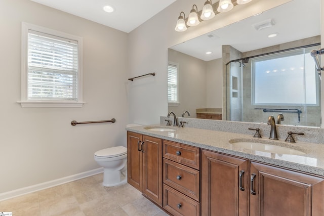 bathroom with vanity, a shower with door, toilet, and a wealth of natural light